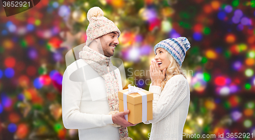 Image of smiling couple in winter clothes with gift box