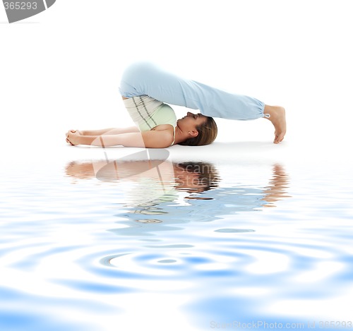 Image of halasana plow pose on white sand #2