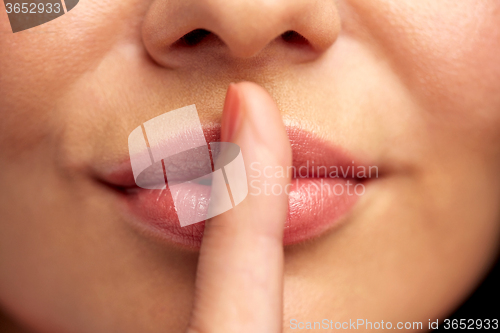 Image of close up of young woman holding finger on lips