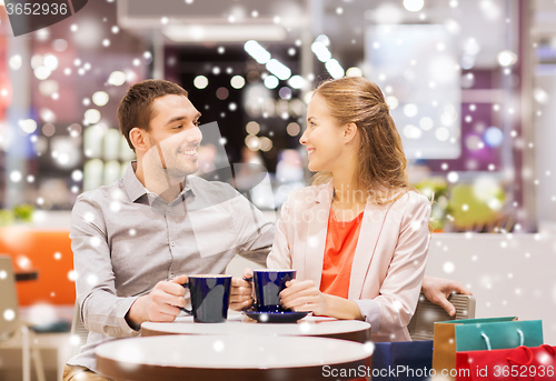 Image of happy couple with shopping bags drinking coffee