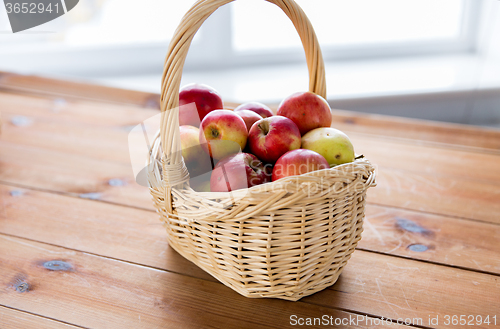 Image of close up of basket with apples on wooden table