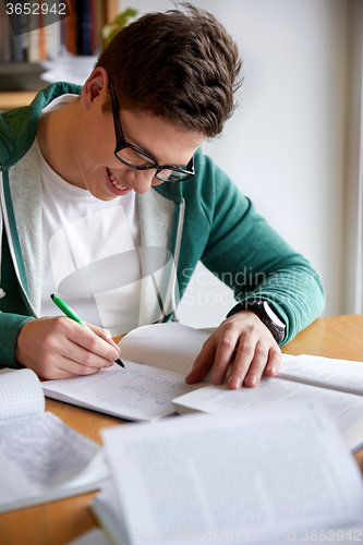 Image of happy student boy writing to notebook in library