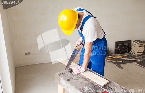 Image of close up of builder with arm saw sawing board