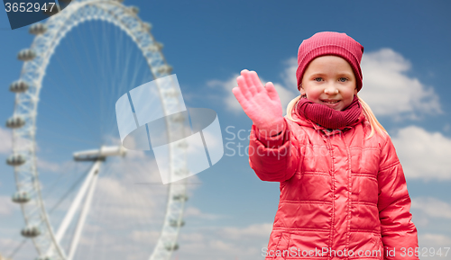 Image of happy little girl waving hand over ferry wheel