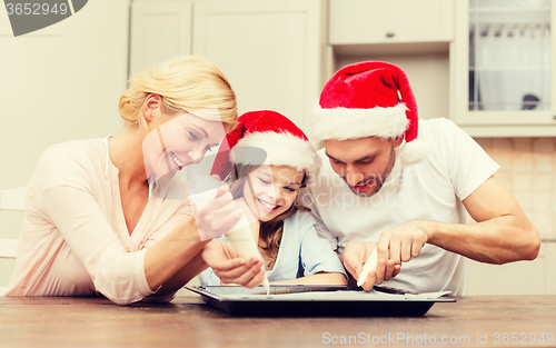 Image of happy family in santa helper hats making cookies