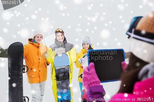 Image of happy friends with snowboards and tablet pc