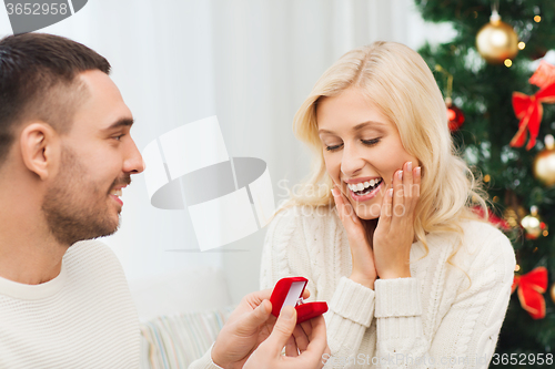 Image of man giving woman engagement ring for christmas