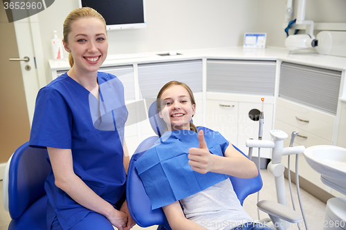 Image of happy female dentist with patient girl at clinic