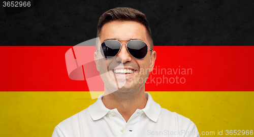 Image of face of smiling man in sunglasses over german flag