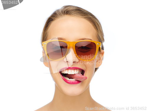 Image of happy young woman in sunglasses showing tongue