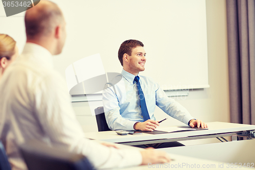 Image of group of smiling businesspeople meeting in office
