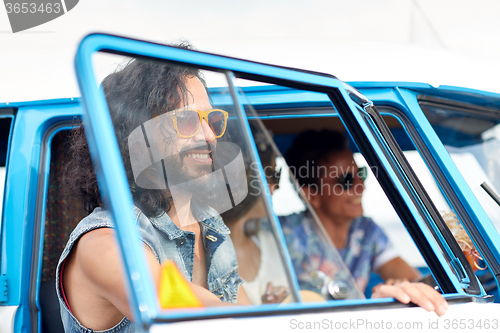 Image of smiling young hippie friends in minivan car