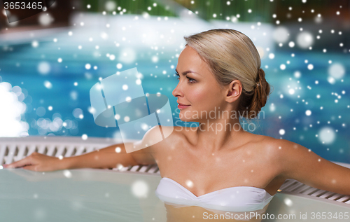 Image of happy woman sitting in jacuzzi at poolside