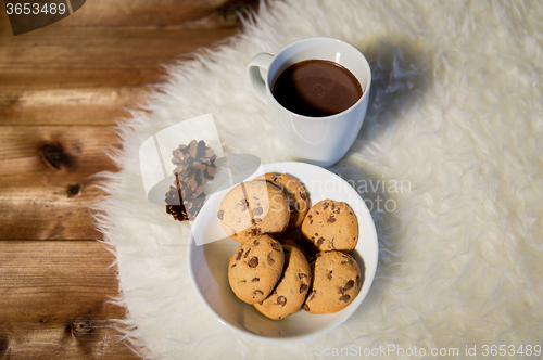 Image of cups of hot chocolate with cookies on fur rug