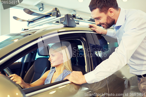 Image of happy couple buying car in auto show or salon