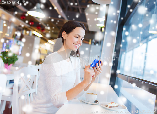Image of smiling woman with smartphone and coffee at cafe
