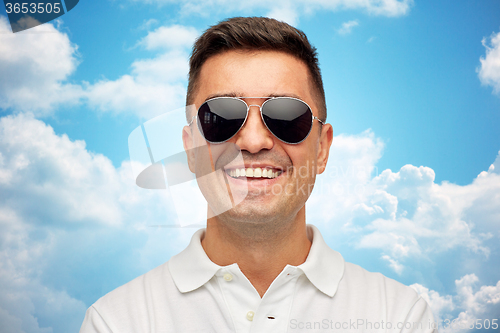 Image of face of smiling man in sunglasses over blue sky