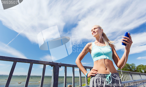 Image of happy woman with smartphone and earphones outdoors