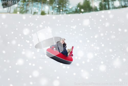 Image of happy teenage girl sliding down on snow tube