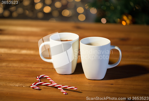 Image of christmas candy canes and cups on wooden table