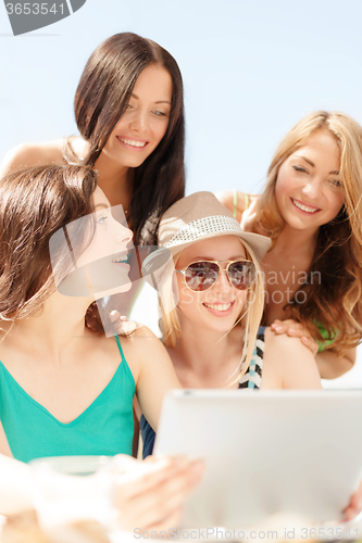 Image of smiling girls looking at tablet pc in cafe