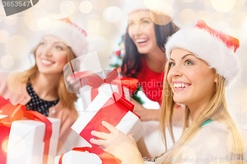 Image of happy women in santa hats with christmas gifts