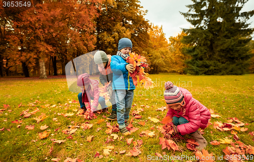 Image of group of children collecting leaves in autumn park