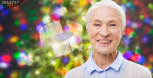 Image of happy senior woman face over christmas lights