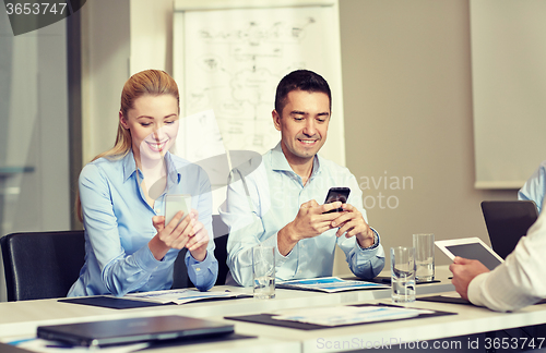 Image of smiling business people with smartphones in office