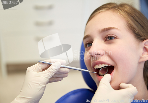 Image of hands with dental mirror checking girl teeth