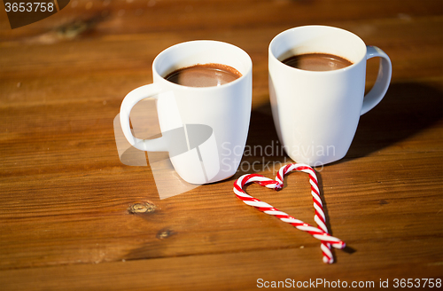 Image of christmas candy canes and cups on wooden table