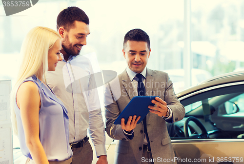 Image of happy couple with car dealer in auto show or salon