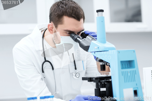 Image of young scientist looking to microscope in lab