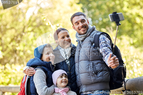 Image of happy family with smartphone selfie stick in woods