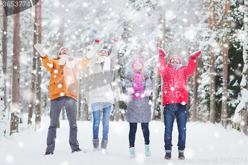 Image of group of happy friends playin with snow in forest