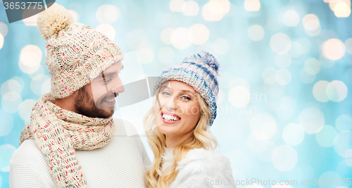 Image of smiling couple in winter clothes over blue lights