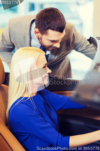 Image of happy couple buying car in auto show or salon