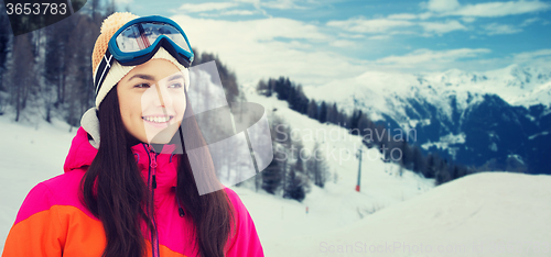 Image of happy young woman in ski goggles over mountains