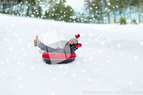 Image of happy teenage girl sliding down on snow tube