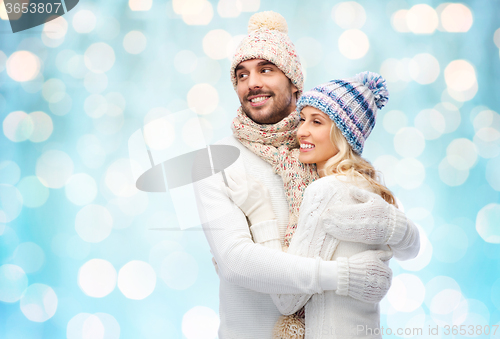 Image of happy couple in winter clothes hugging over lights