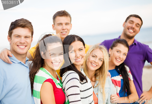 Image of group of happy friends hugging on beach