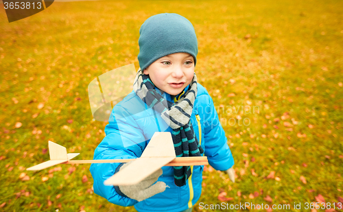 Image of happy little boy playing with toy plane outdoors