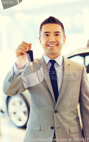 Image of happy man showing key at auto show or car salon