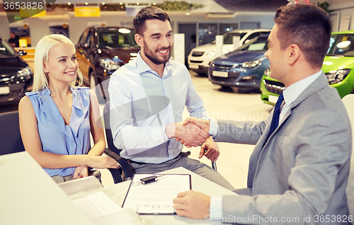 Image of happy couple with car dealer in auto show or salon