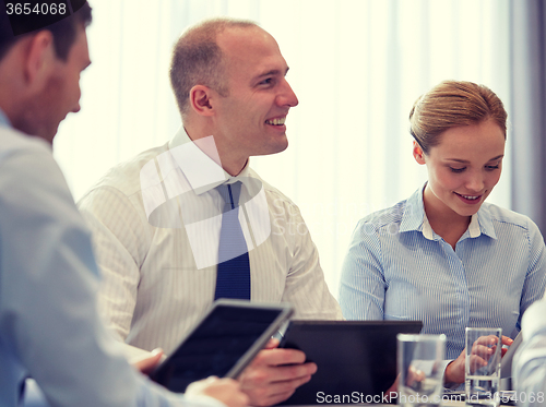 Image of smiling businesspeople with tablet pc in office