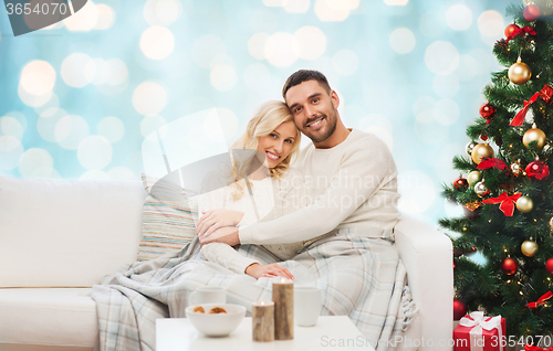 Image of happy couple hugging on couch at christmas