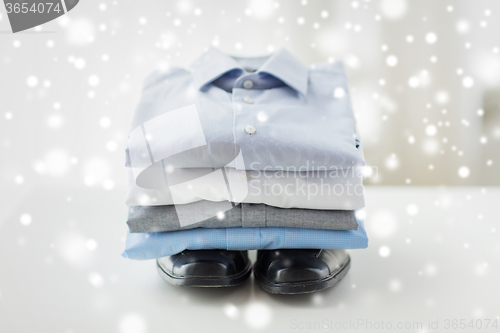 Image of close up of folded male shirts and shoes on table