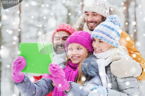 Image of smiling friends with tablet pc in winter forest