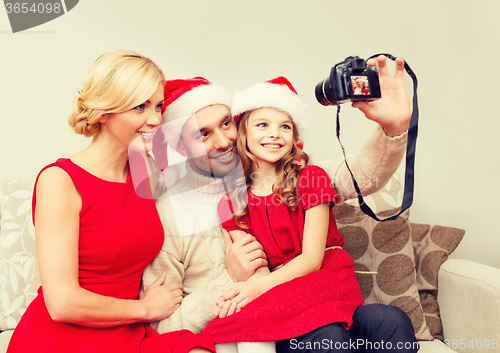 Image of smiling family in santa helper hats taking picture