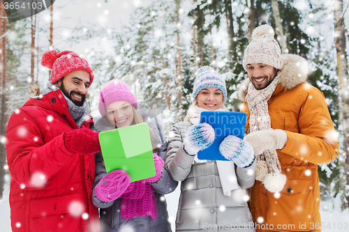 Image of smiling friends with tablet pc in winter forest